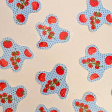 Load image into Gallery viewer, Several light blue star-shaped stickers with a red tomato and cherry tomato pattern scattered on a light beige background.